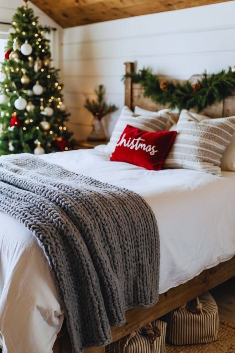 A cozy knit throw blanket draped over a rustic bed in a farmhouse bedroom adorned with Christmas decor